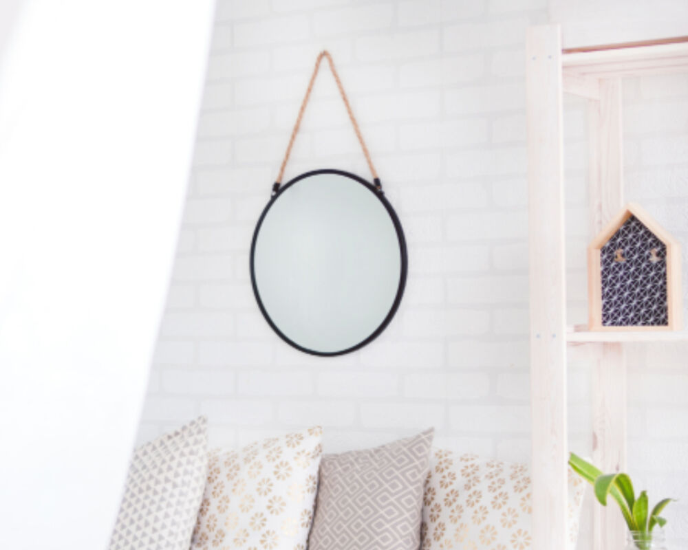 Round wall mirror above a sofa with cushions